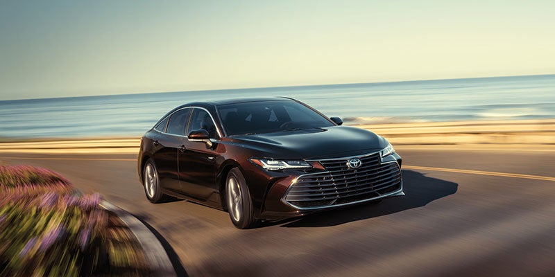 Front view of a 2021 Toyota Avalon Hybrid driving on a coastal road